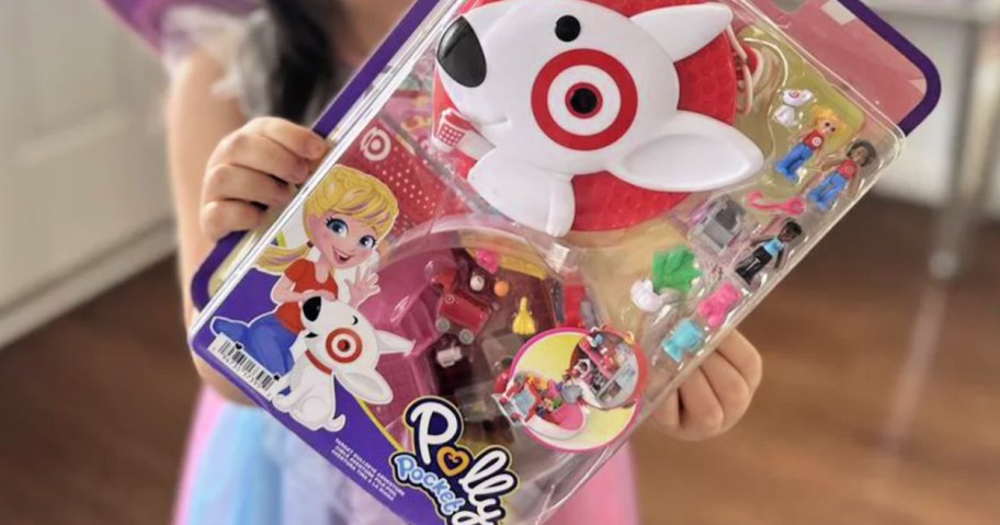 little girl holding up polly pocket set from target