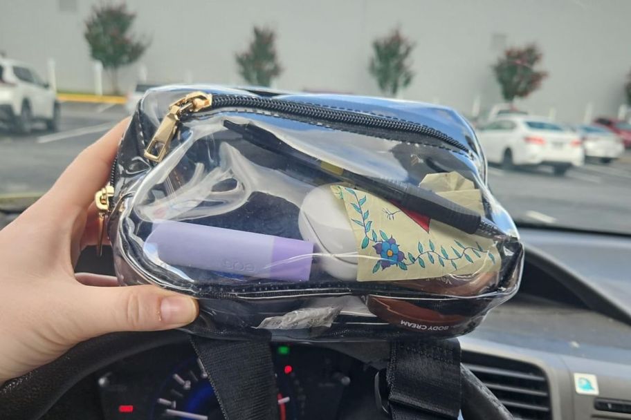 A person in a car holding a filled Telena Clear Belt Bag at a Stadium