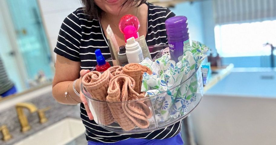 woman holding The Home Edit Clear Plastic High Wall Turntable Organizer w/ Removable Dividers filled with bathroom items