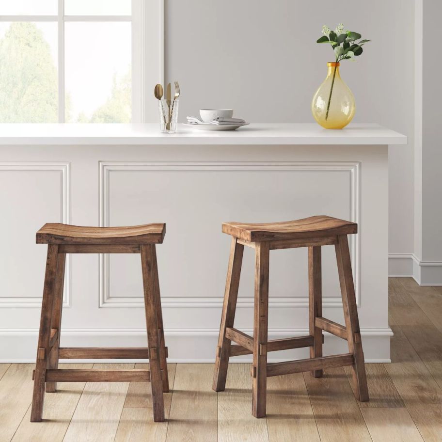 two brown colored wooden counter height barstools in a kitchen at a bar