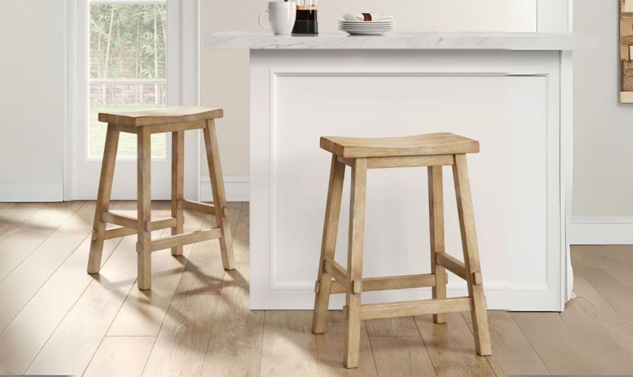 two natural colored wooden counter height barstools in a kitchen at a bar