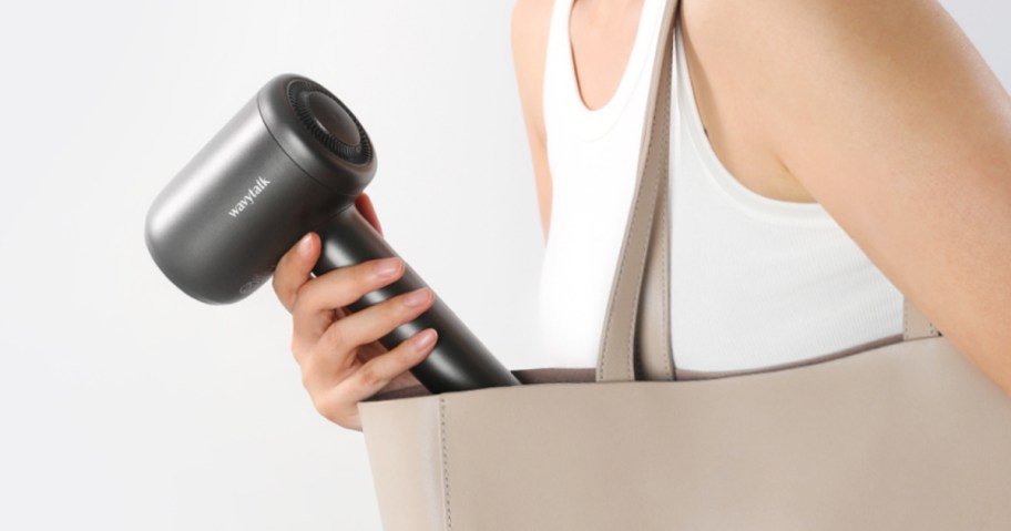 hand pulling ionic hair dryer out of beige tote bag 