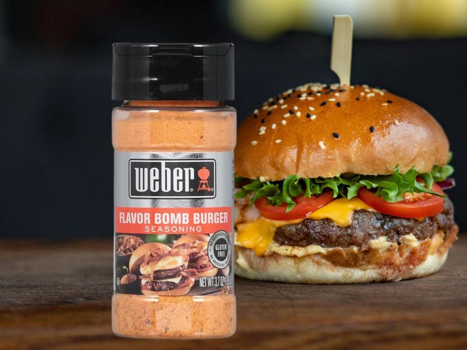 Weber Flavor Bomb Seasoning, 3.7 Ounce Shaker in front of a burger
