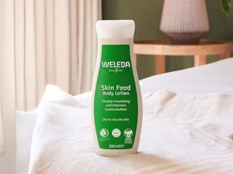 Weleda Skin Food Body Lotion 6.8oz bottle on bed
