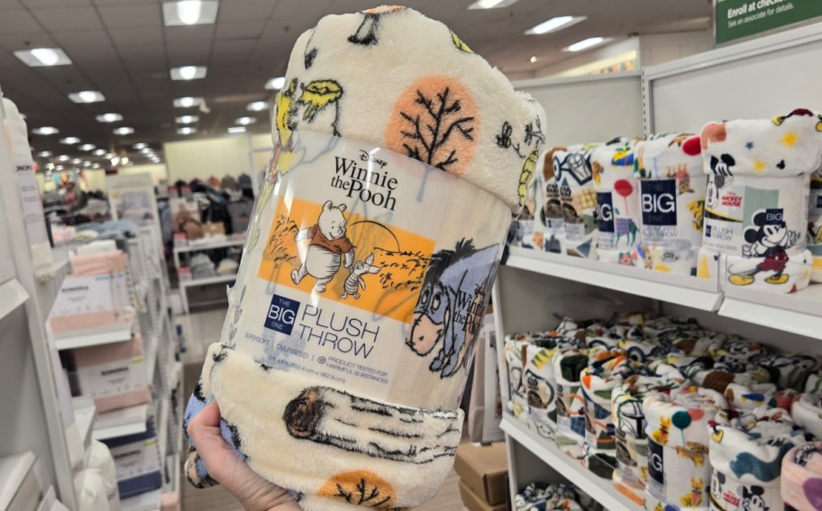 Winnie the Pooh plush throw in womans hand displayed at the store