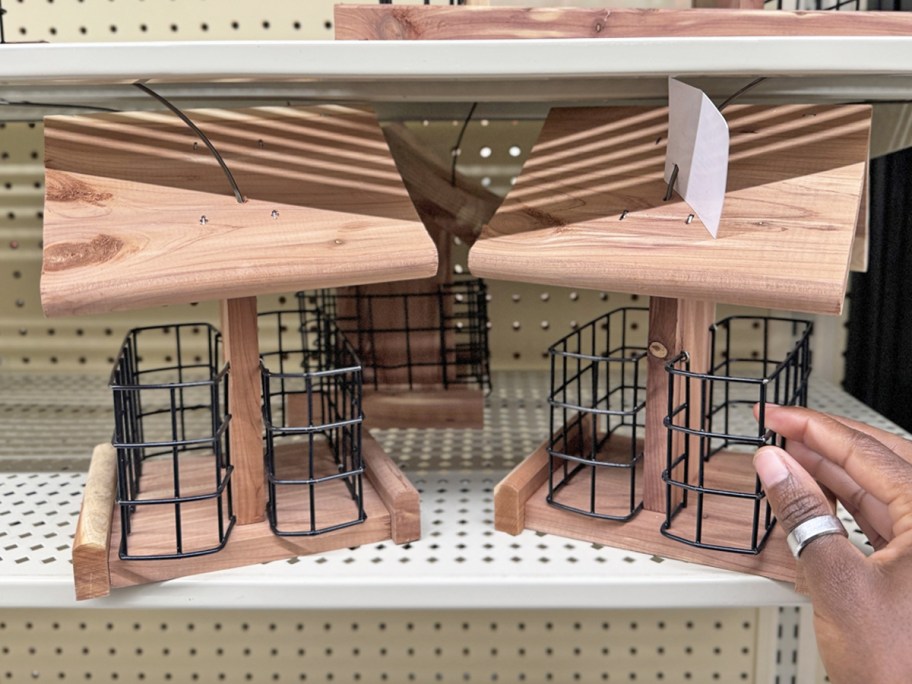 hand touching wood bird feeder on store shelf