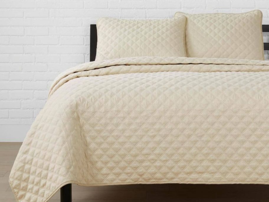 A bed with a cream colored comforter