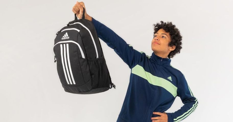 boy holding up adidas backpack