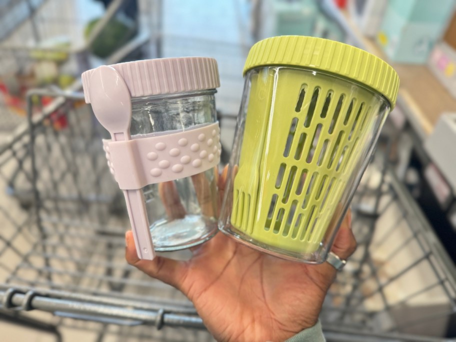 hand holding a pink and yellow on the go food containers with spoons