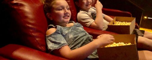 kids watching movie in amc theater with popcorn in laps