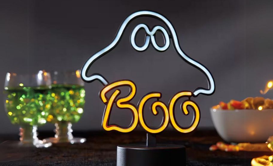 a boo ghost neon look led lamp on a table top with drink and snacks