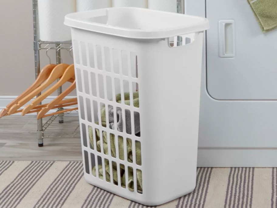 white hamper with laundry next to washer