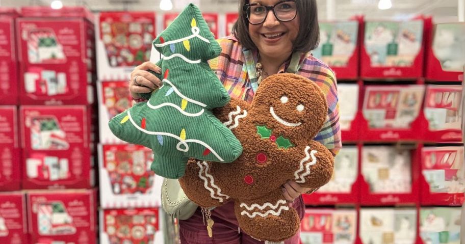 woman holding a christmas tree and gingerbread man pillow in store