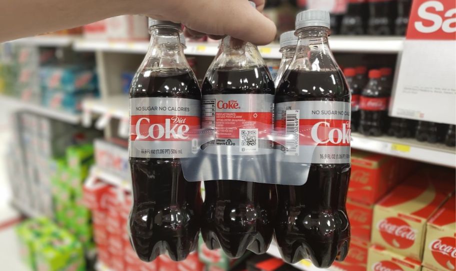 a mans hand holding a 6 pack of diet coke