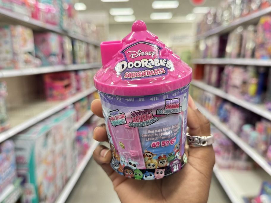 a womans hand holding a disney dorables container.