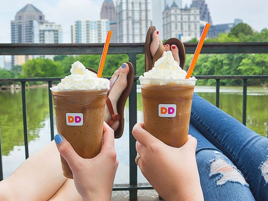 2 people relaxing on balcony holding Dunkin frozen coffees