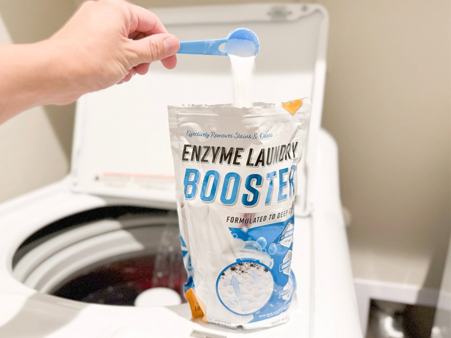 hand pouring powder into active enzyme laundry booster bag on washer