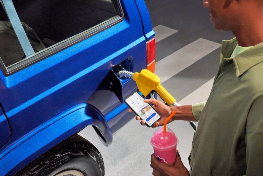 man pumping gas while looking at the get upside app