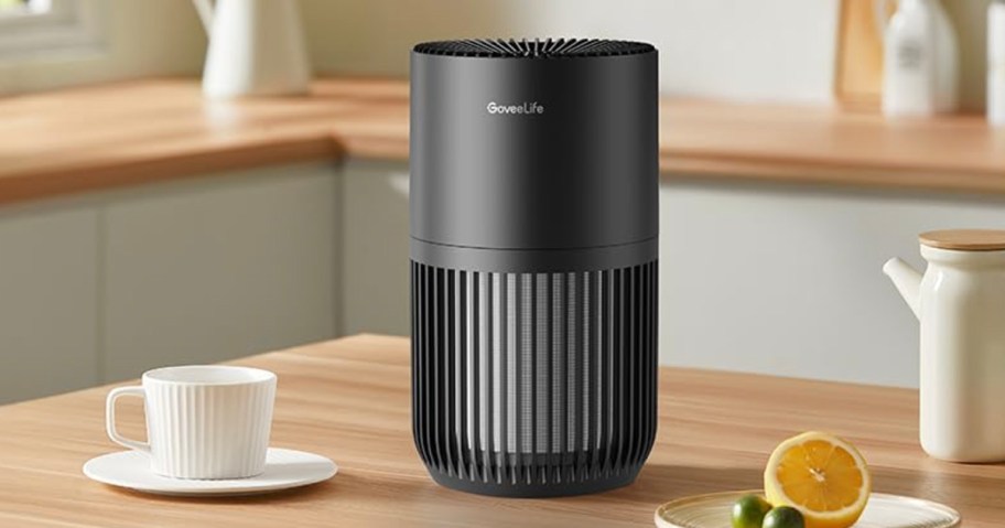 black air purifier on table with cup 