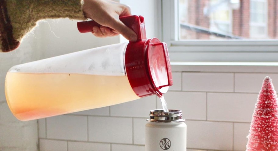 hand holding pitcher and using ti to pour water into cup