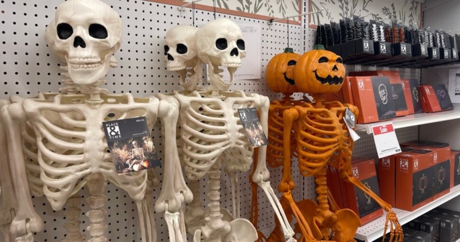 white skeletons and orange pumpkin head skeletons Halloween decor hanging on display in a store