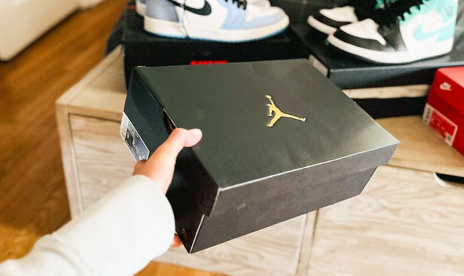 a womans hand holding a nike air jordan box