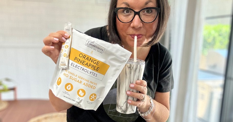 woman holding back of just ingredients packets and drink