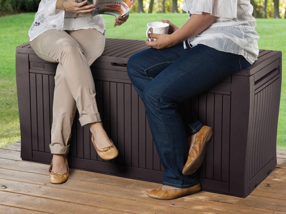 two people sitting on brown keter storage box