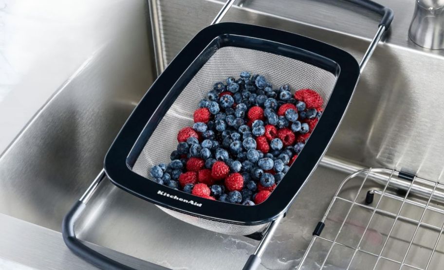 a mesh strainer expanded to fit across a kitchen sink, and filled with fresh berries