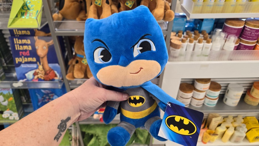 hand holding a batman kohls cares plush in a store aisle