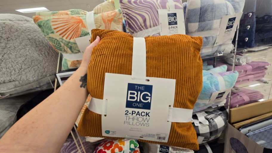 hand holding up a two pack of the big one throw pillows in a kohls store