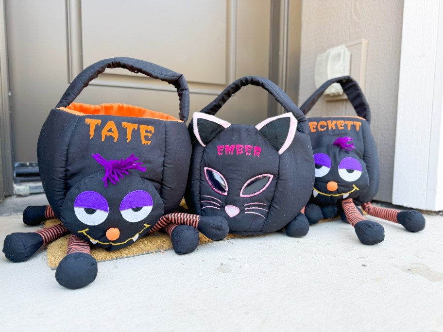 kid's personalized Halloween treat bags in the shape of spiders and cats sitting on a front porch