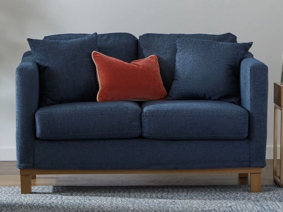 navy blue sofa with wood legs and red pillow