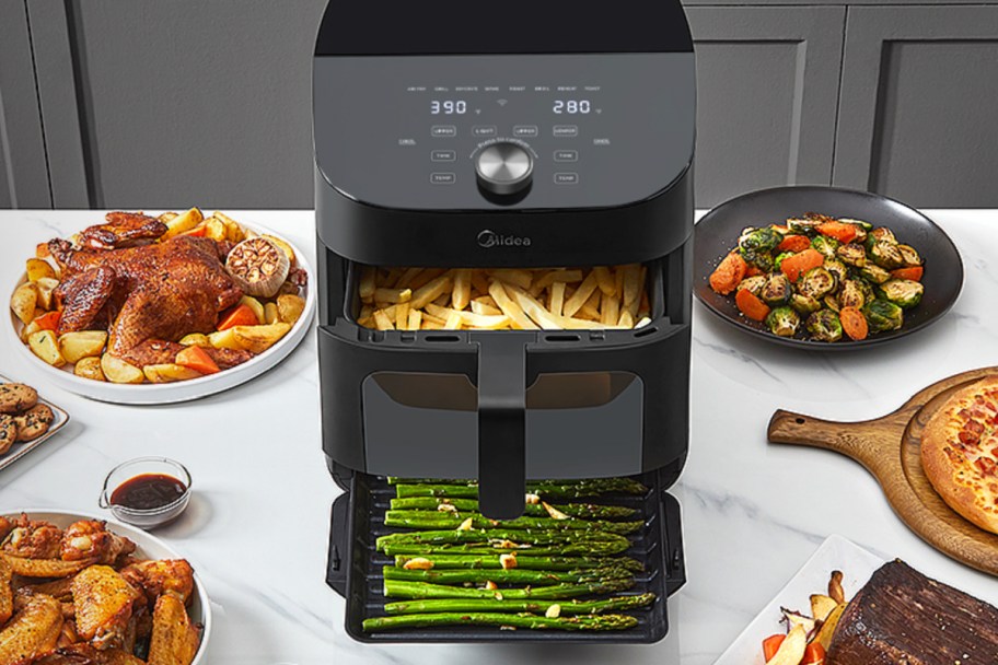 air fryer with two baskets and food surrounding it