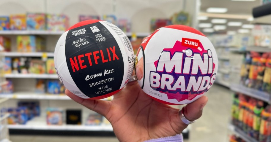 hand holding up 2 Mini Brands Netflix Capsules in the packaging
