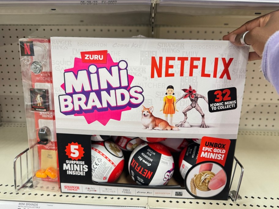 hand reaching for the display box of a Mini Brands Netflix Capsule