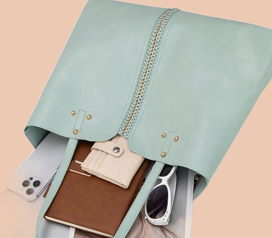 sage green purse with items spilling out