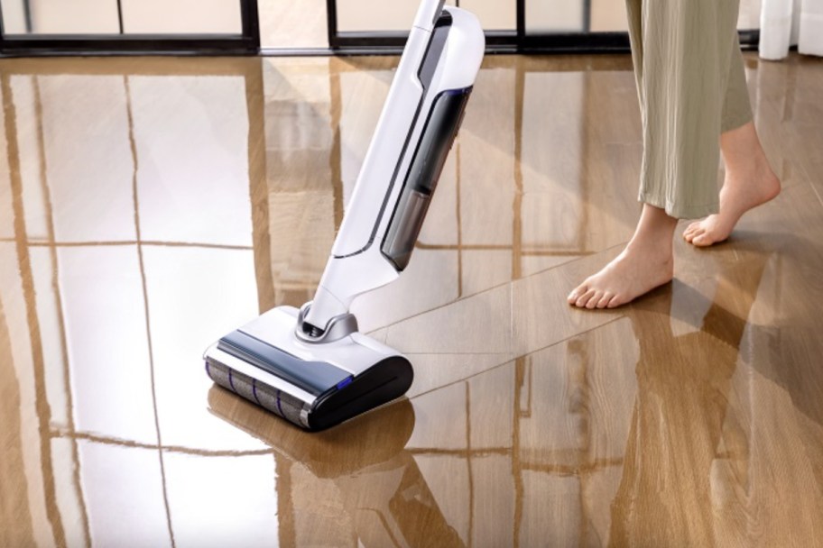 person standing next to stick vac and mop