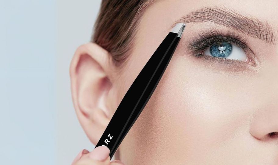 a woman holding a pair of tweezers to her brow