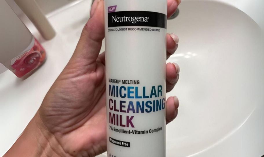 a womans hand holding a bottle of neutrogena micellar cleansing milk