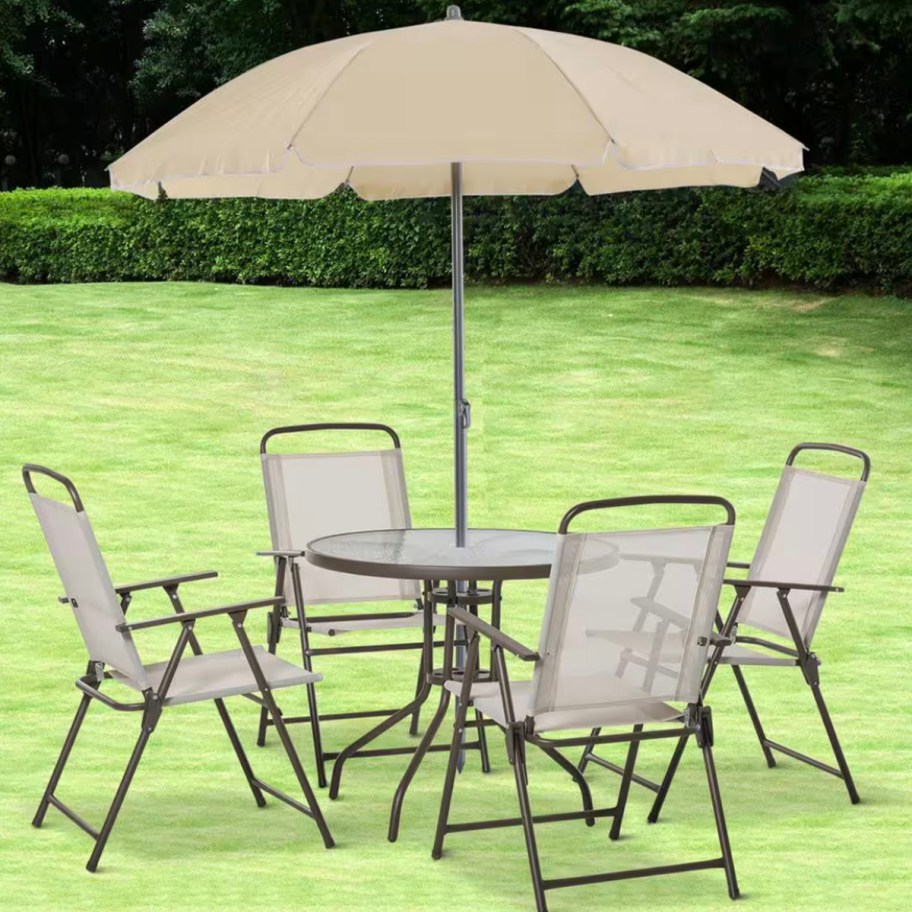 tan dining set with 4 chairs and an umbrella outdoors