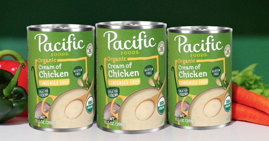 three Pacific Foods Organic Cream of Chicken Soup cans on counter with vegetables next to them