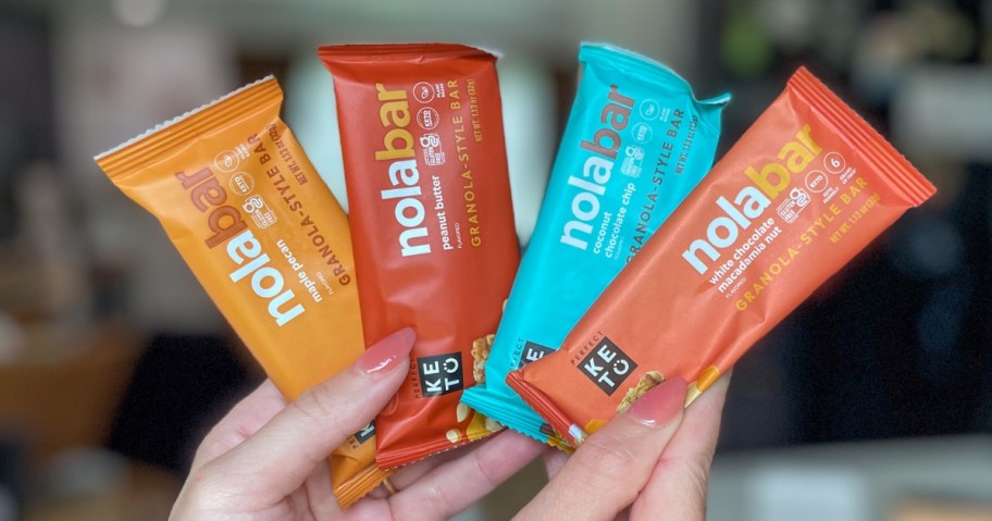hand holding up 4 different Perfect Keto Nola Bars in the wrappers