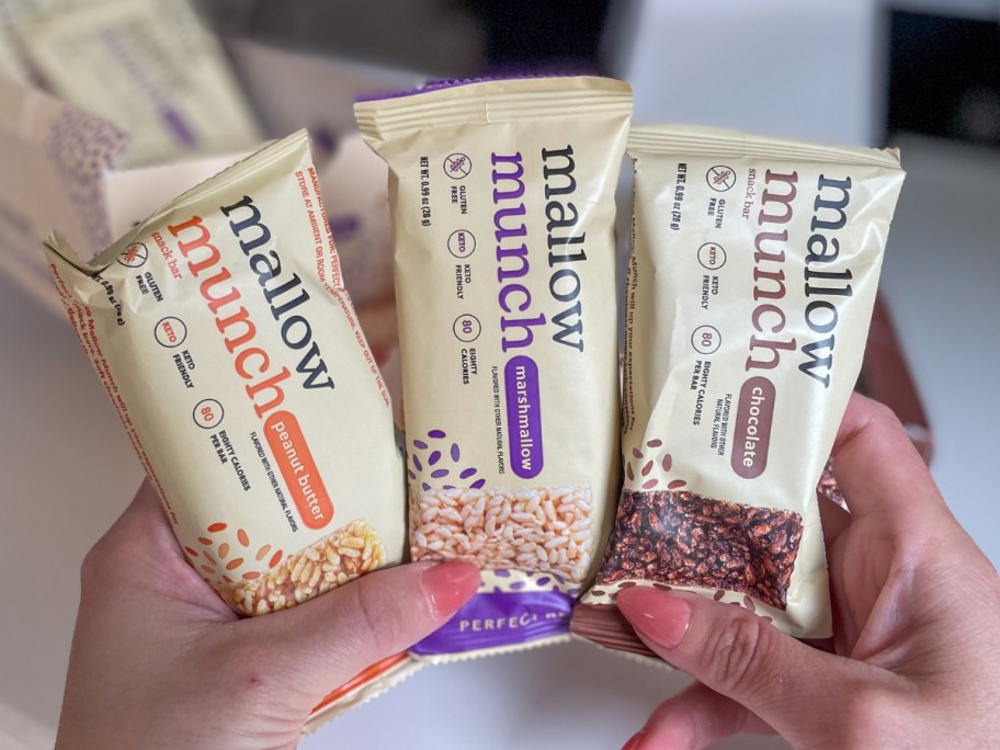 hand holding up 3 Perfect Keto Mallow Munch bars in the wrappers