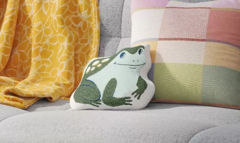 a frog shaped throw pillow on a sofa