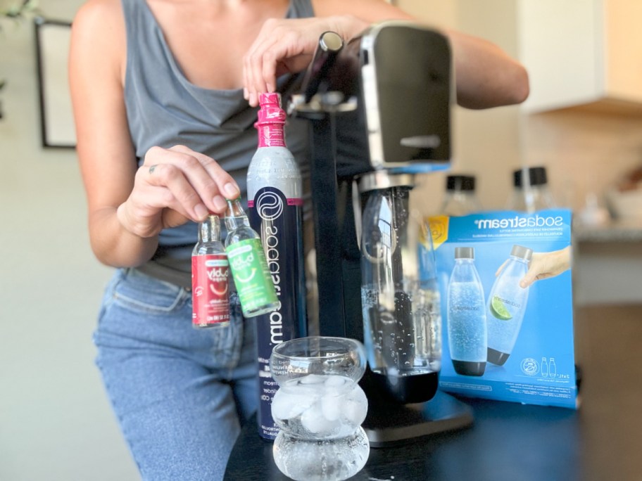 woman standing behind a sodastream art machine with accessories