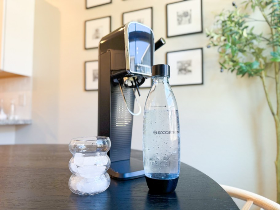 sodastream art machine on a table with a filled bottle of water plus a glass of carbinated water