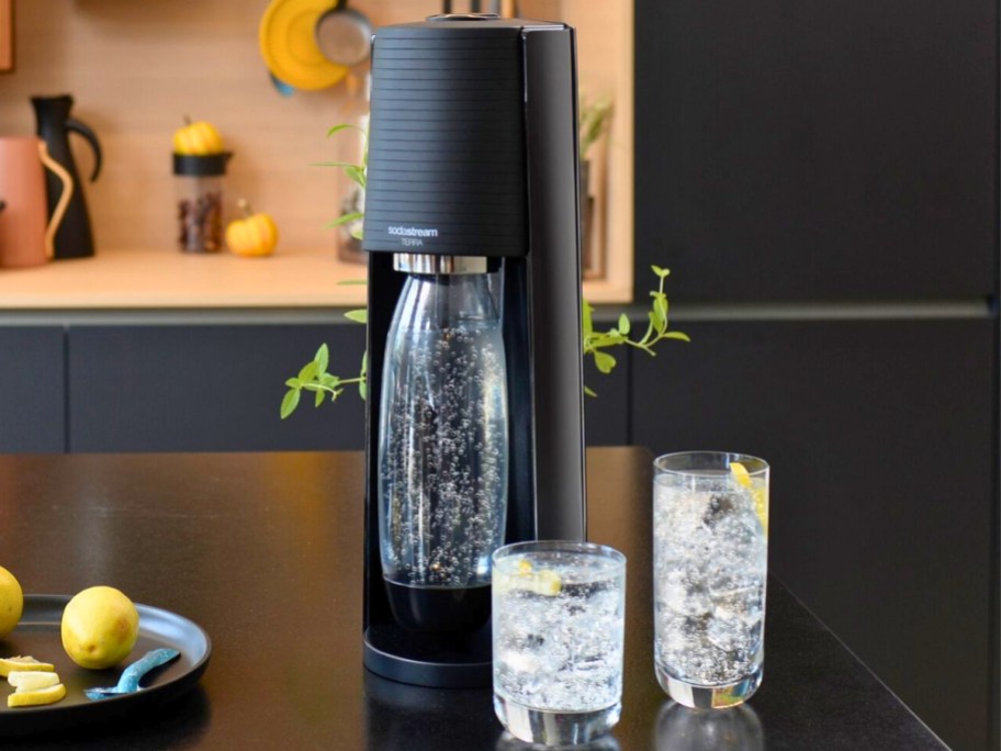 black SodaStream Terra machine with 2 glasses of sparkling water on a kitchen counter