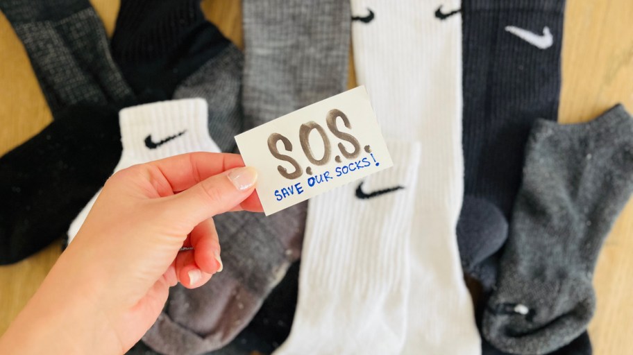 hand holding an sos save our socks with different single socks in background