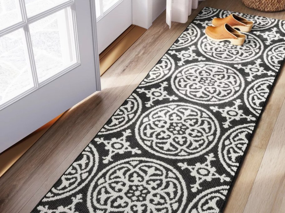 a long black and white medallion runner rug in a hallway